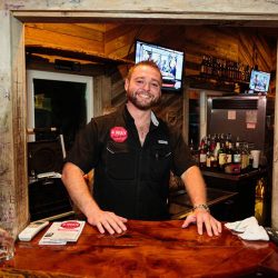 Smiling server behind a table at our bar and grill - The 4 Way Bar and Grill