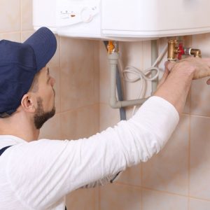 A man performing maintenance on a water heater.