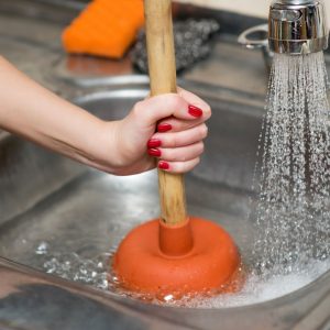 someone using a plunger on a sink