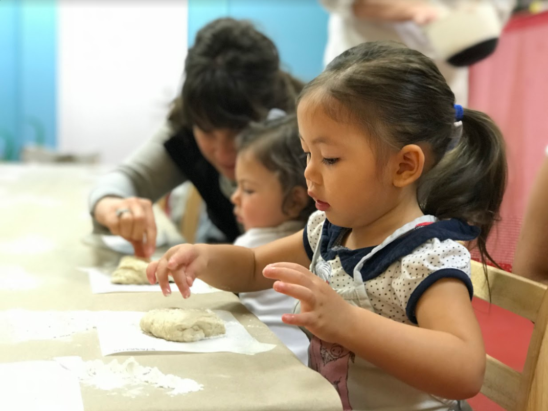 A picture of children sitting at a table and working with flour at The Art Farm NYC.