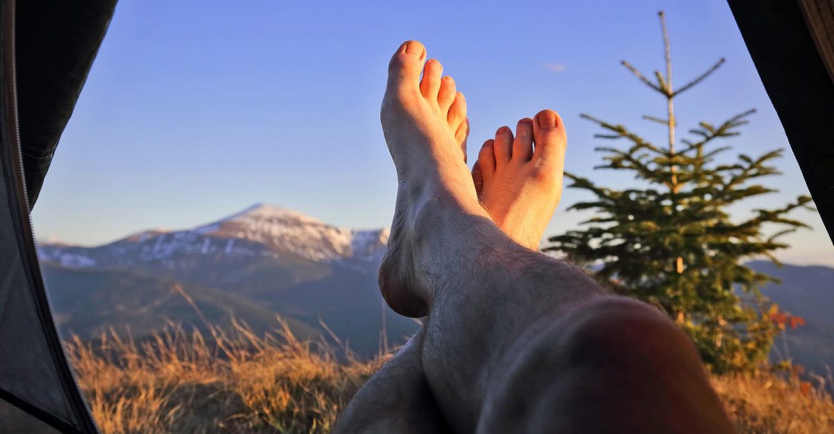 Man's legs and feet sticking out of their tent while they relax