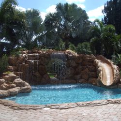 Small inground pool with slide and waterfall.