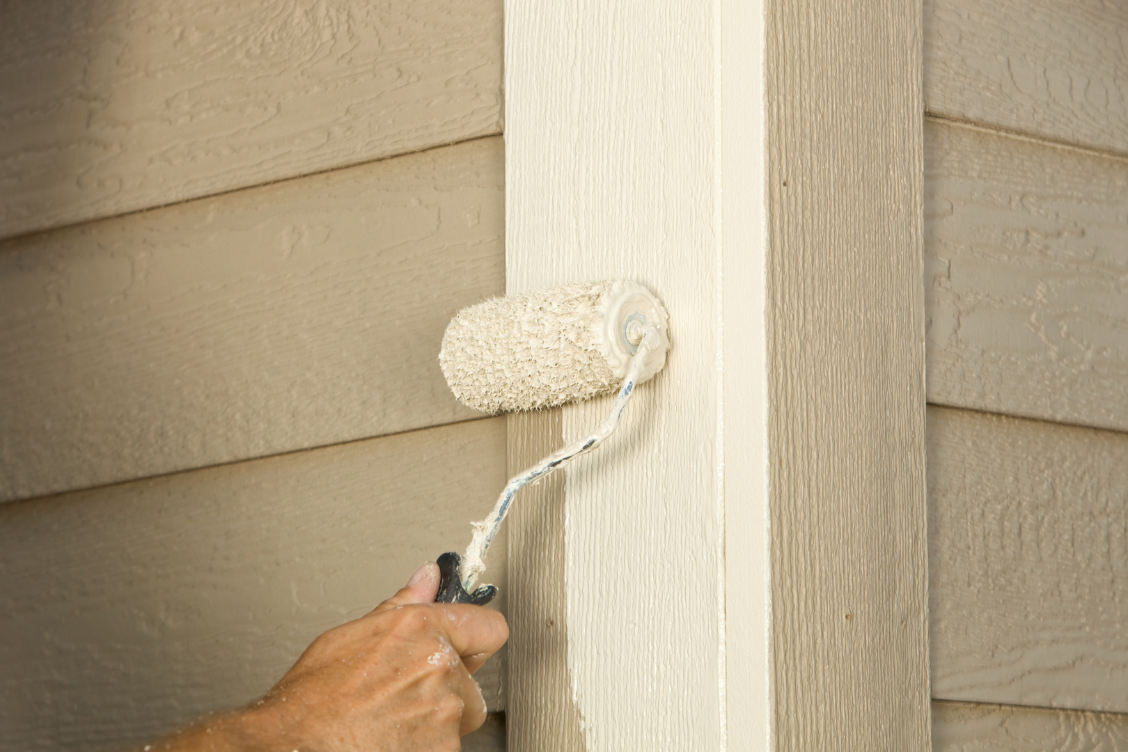 paint roller painting exterior of home