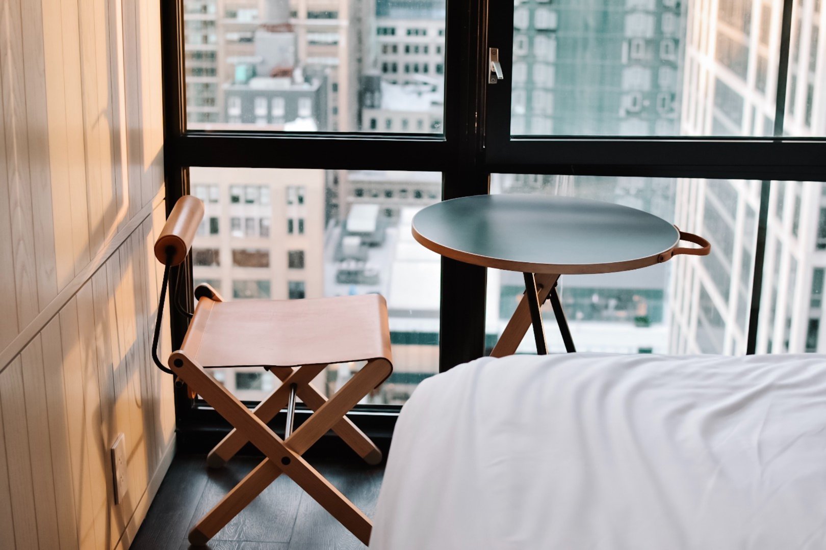 wooden chair and table in front of a large window in a big city