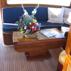An image of a custom wooden deck table with cushioned booth made by Dennis Boatworks.