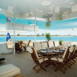 An image of a deck with outdoor lounging furniture and 10-person dining table made by Dennis Boatworks.