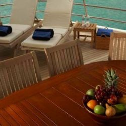 An image of the owner's deck on a yacht with custom wood flooring, two reclining chairs, and a wooden dining table created by Dennis Boatworks.