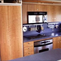 Image of a custom kitchen with light wood cabinets and dark countertops designed by Dennis Boatworks.