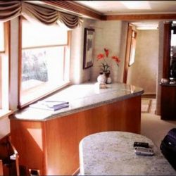 An image of spacious, custom interior with well-lit windows and wooden furnishing made by Dennis Boatworks.