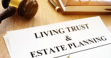 A document titled "Living Trust & Estate Planning" lays on a table with a pen, gavel, and a book.