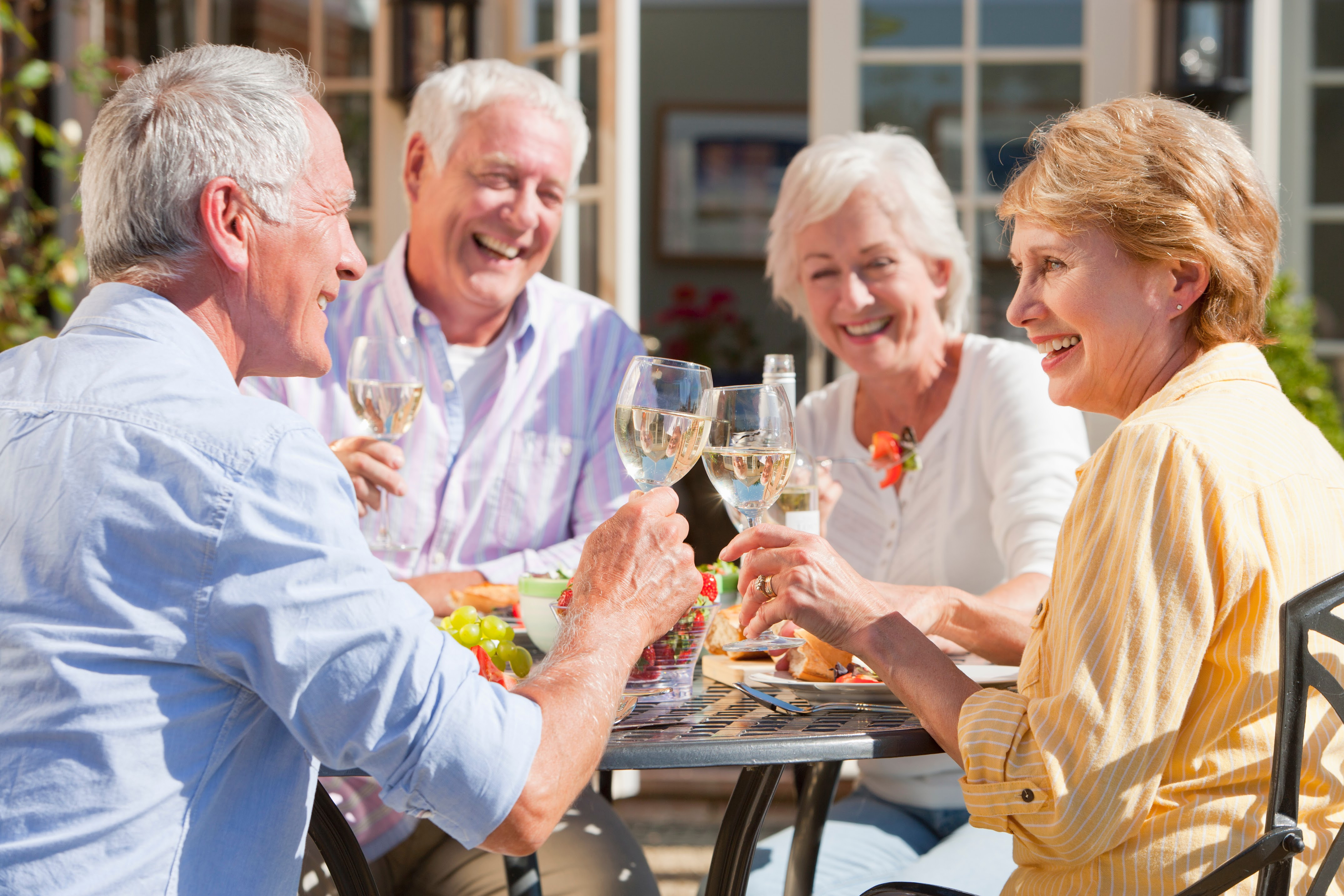 old people sitting around a table laughing and talking and drinking wine outside
