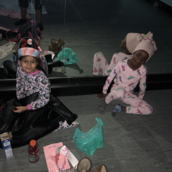 Two gilrs in pajamas sitting on floor and leaning against mirror - Fancy Feet Dance