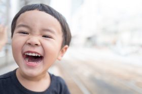 A young boy smiles broadly. Photo by kazuend on Unsplash.