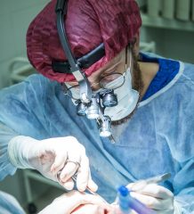 A man wearing a medical suit and performing surgery on a patient. Photo by Olga Guryanova on Unsplash.