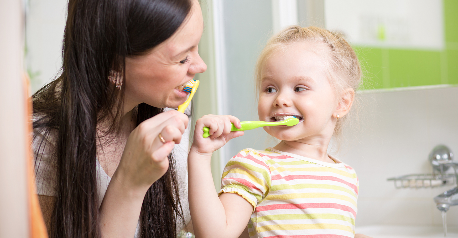 Mother with daughter teeth brushing in bathroom