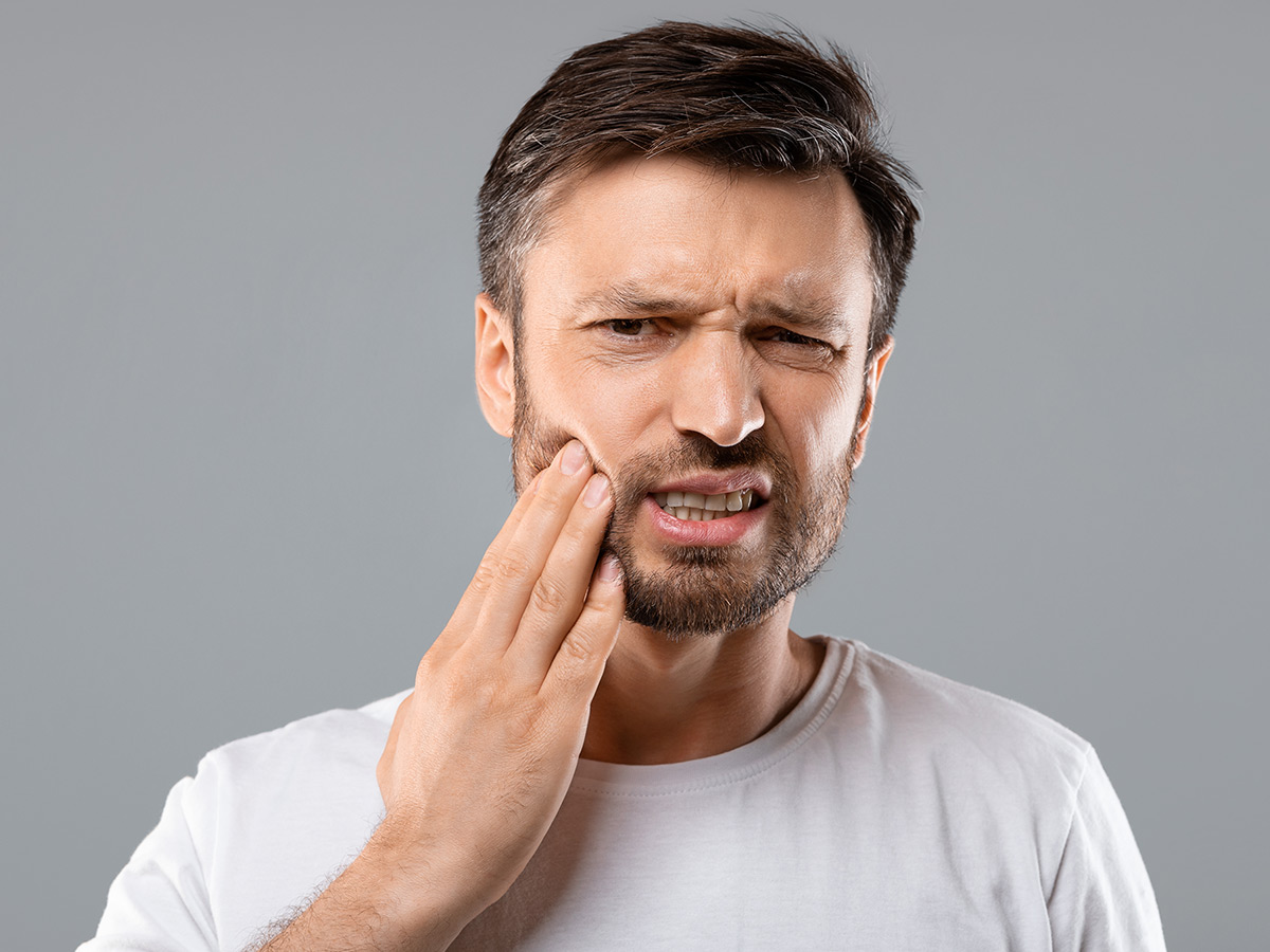 A man feeling some tooth pain after anesthesia has worn off