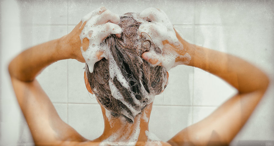 Woman scrubs head with lice shampoo in the shower.