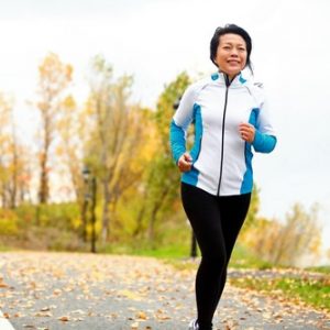 Photo of an asian woman running in the fall.