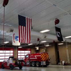 Inside of a firehouse with flags hanging from the ceiling - ND Flag Pole Guy