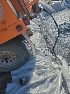 gray sludge being pumped out of a vac trailer into a holding cell