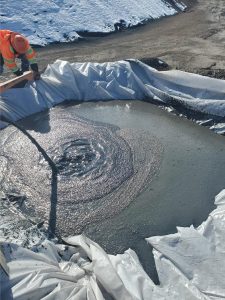 gray sludge in a plastic-lined cell