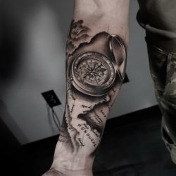 Black and grey realism tattoo of a compass and map on the right forearm.