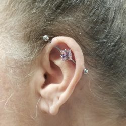 Industrial piercing with a 14 gauge internally threaded bar and a pink crystal adornment.