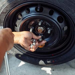 Hands of mechanic changing a flat car tire.