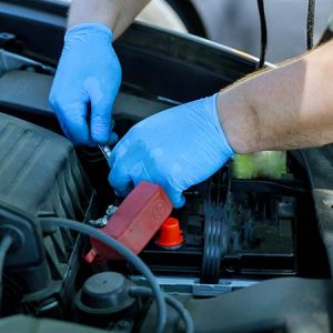 Mechanic checking battery electrical wires on a car.