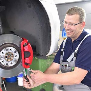 Car mechanic repairs brakes of a vehicle.